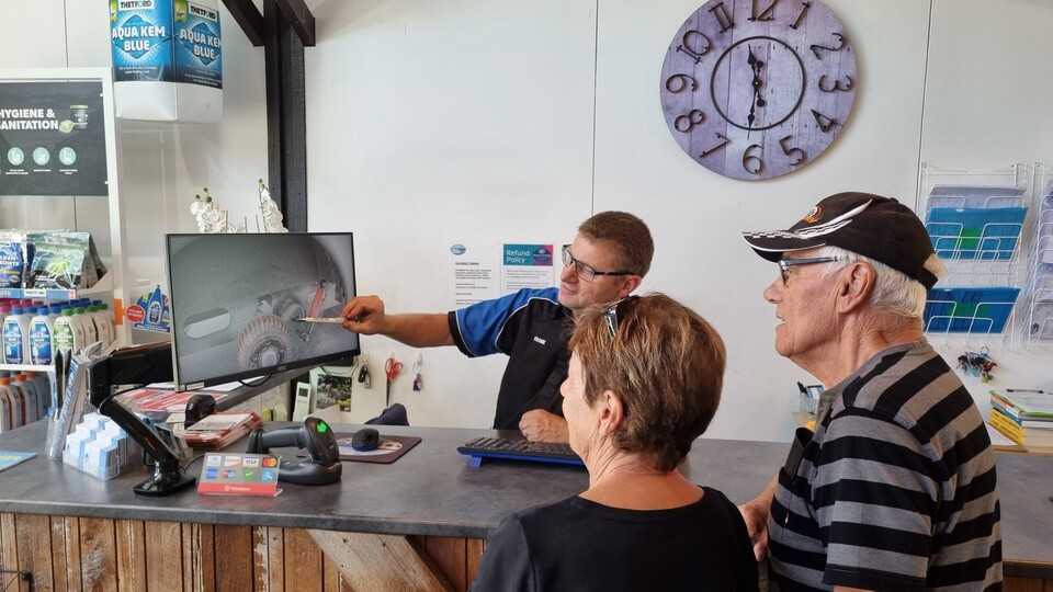 Mechanic explaining caravan repairs to customer during service